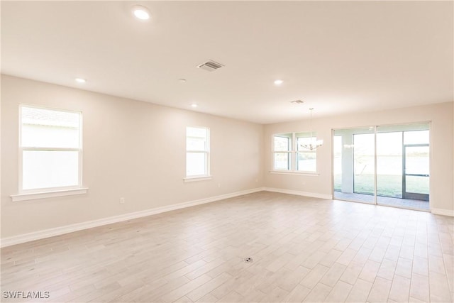 unfurnished room featuring a chandelier and light hardwood / wood-style floors