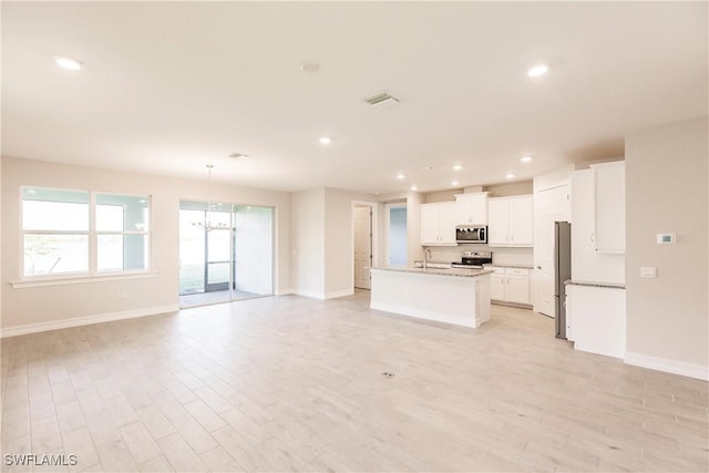 kitchen with a center island with sink, white cabinets, light wood-type flooring, and stainless steel appliances