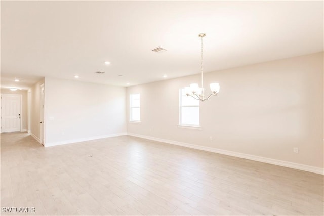 empty room featuring a chandelier and light hardwood / wood-style floors