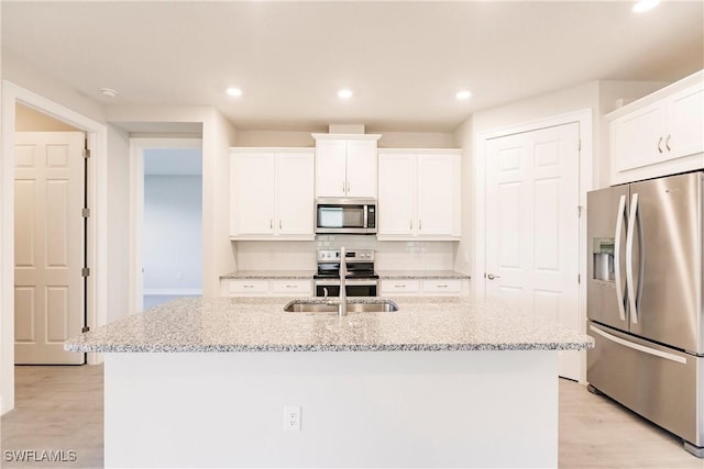 kitchen featuring white cabinets, sink, stainless steel appliances, and an island with sink