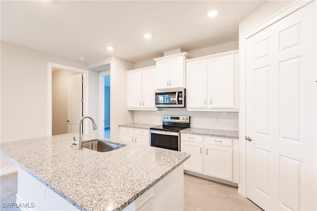 kitchen featuring white cabinets, stainless steel appliances, and a center island with sink