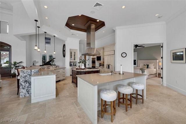 kitchen with decorative light fixtures, sink, island range hood, a large island, and a breakfast bar area