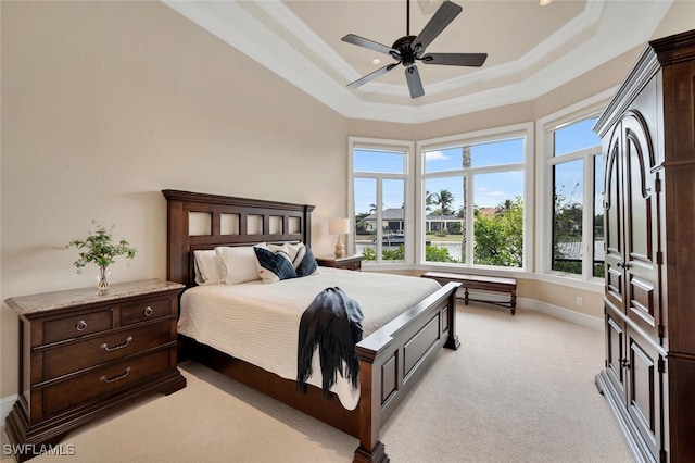 bedroom featuring baseboards, a raised ceiling, a ceiling fan, light colored carpet, and crown molding