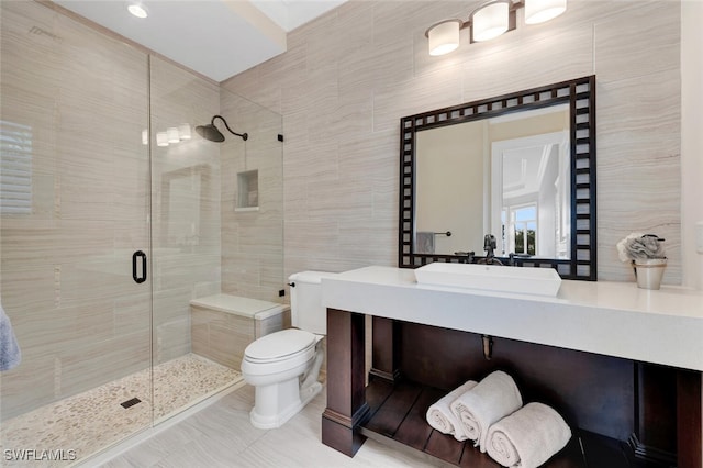 bathroom featuring toilet, vanity, tile walls, and a shower with door