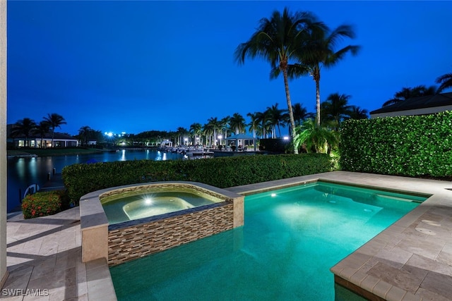 pool at twilight with a water view and an in ground hot tub