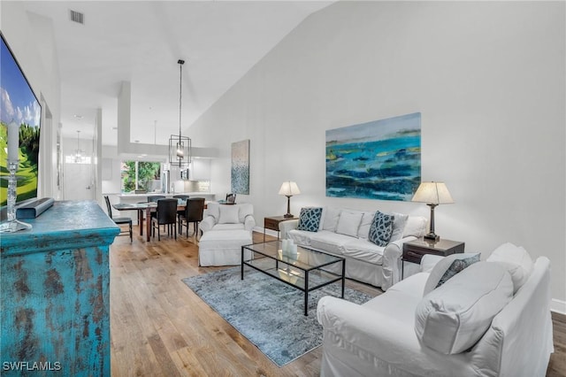 living room with light wood-type flooring and high vaulted ceiling