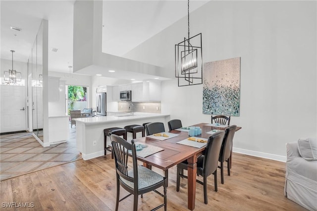 dining area with a high ceiling, light wood-type flooring, and sink