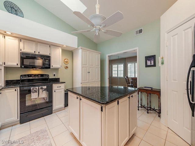 kitchen featuring black appliances, light tile patterned flooring, dark stone counters, and vaulted ceiling