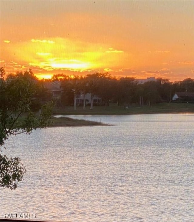 yard at dusk featuring a water view