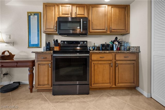 kitchen featuring black range with electric cooktop, dark stone counters, and light tile patterned flooring