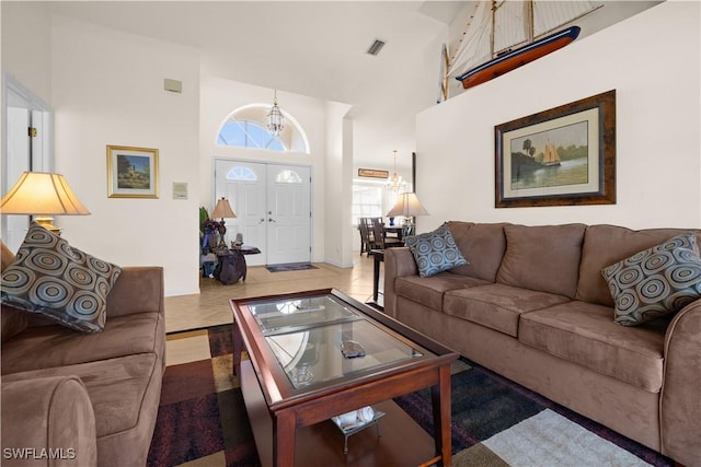 living room with a towering ceiling, tile patterned floors, and a notable chandelier