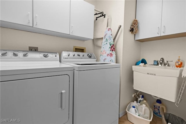 washroom with cabinets, sink, light tile patterned floors, and washer and dryer