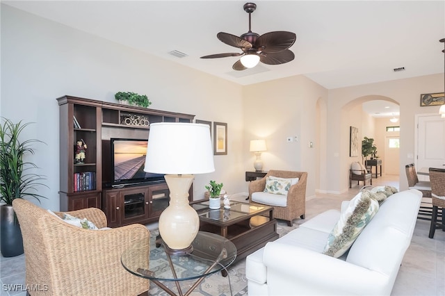 living area with visible vents, arched walkways, and ceiling fan