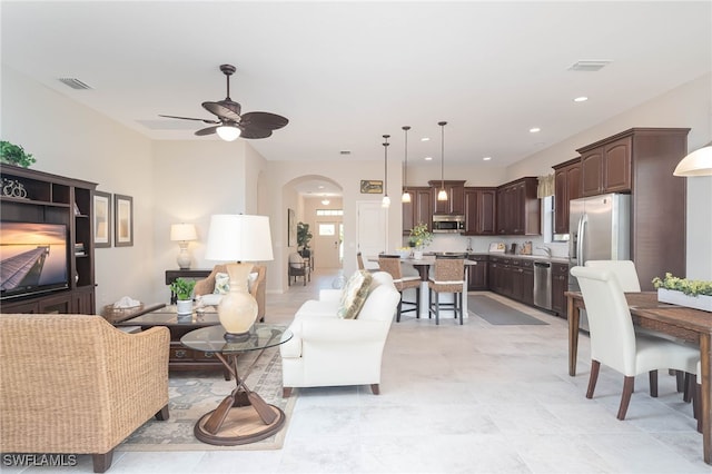 living area featuring recessed lighting, visible vents, arched walkways, and a ceiling fan