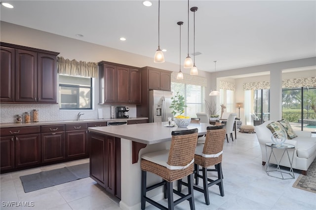 kitchen with a kitchen breakfast bar, stainless steel fridge, a kitchen island, and pendant lighting