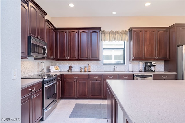 kitchen with backsplash, sink, light tile patterned flooring, and appliances with stainless steel finishes