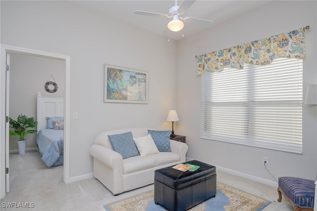living room with baseboards, light colored carpet, and a ceiling fan