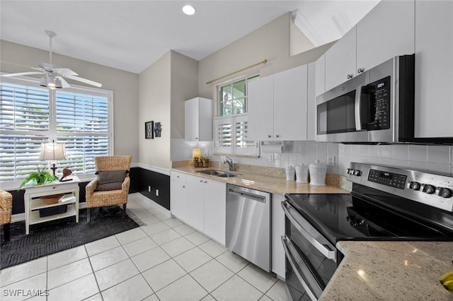 kitchen featuring sink, light stone countertops, appliances with stainless steel finishes, tasteful backsplash, and white cabinetry