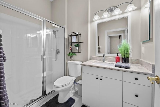 bathroom featuring vanity, a shower with shower door, and toilet