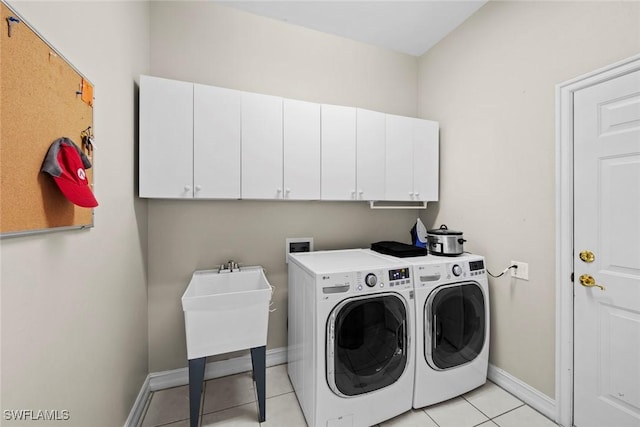 laundry room with cabinets, light tile patterned floors, and washing machine and dryer