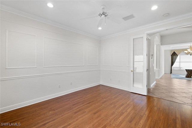 empty room with hardwood / wood-style floors, ceiling fan with notable chandelier, and crown molding