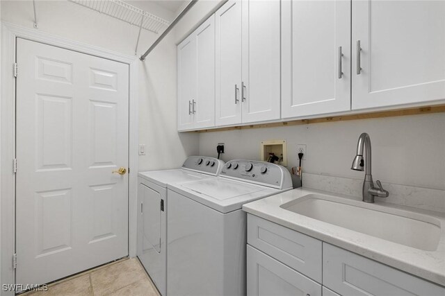 washroom featuring cabinets, separate washer and dryer, sink, and light tile patterned floors