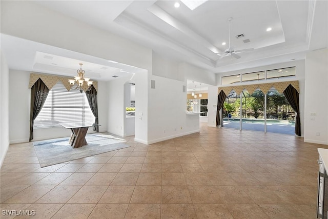 unfurnished room featuring light tile patterned floors, ceiling fan with notable chandelier, and a tray ceiling