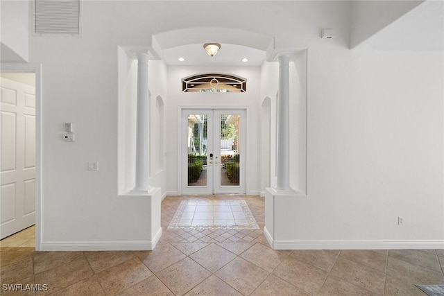 foyer entrance featuring decorative columns, french doors, and light tile patterned floors