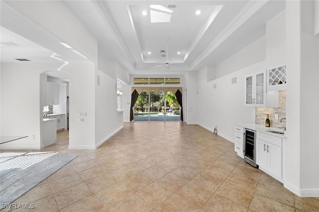 hallway featuring a tray ceiling, wine cooler, sink, and ornamental molding