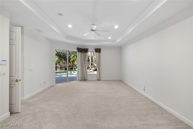 empty room featuring ornamental molding, a tray ceiling, ceiling fan, and light colored carpet