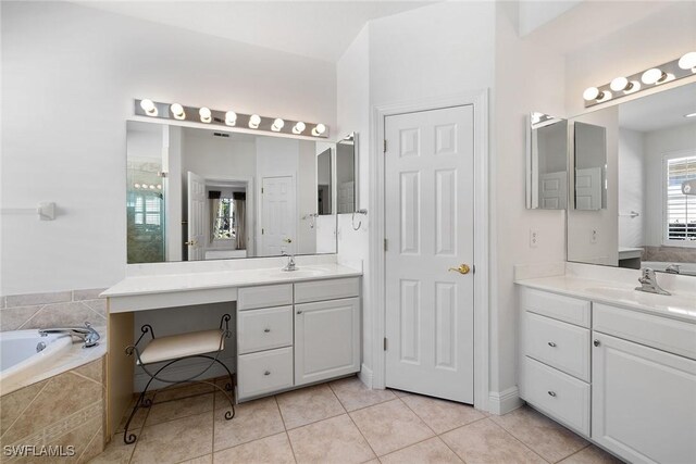 bathroom with tile patterned flooring, vanity, and a relaxing tiled tub