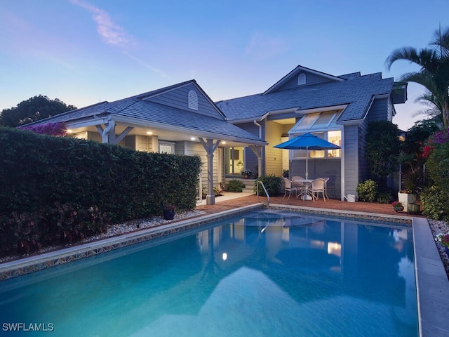 pool at dusk with a patio area