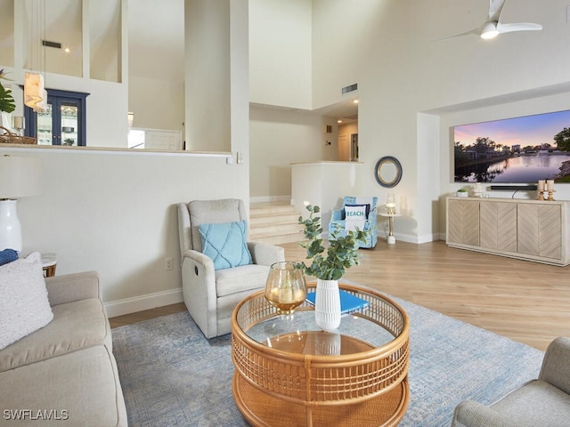 living room with hardwood / wood-style floors, ceiling fan, and a high ceiling