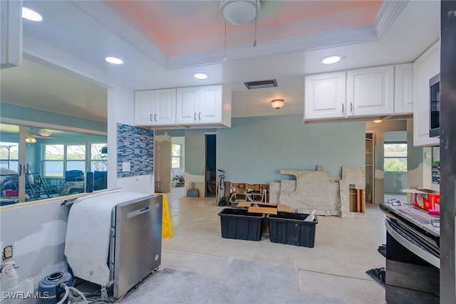 kitchen featuring a raised ceiling, white cabinetry, and ornamental molding