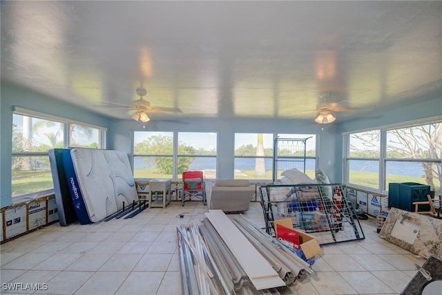 sunroom featuring ceiling fan and a water view