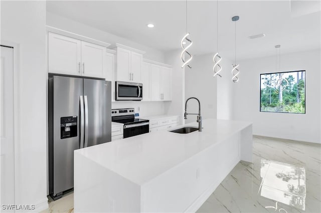 kitchen featuring white cabinets, hanging light fixtures, stainless steel appliances, and a kitchen island with sink