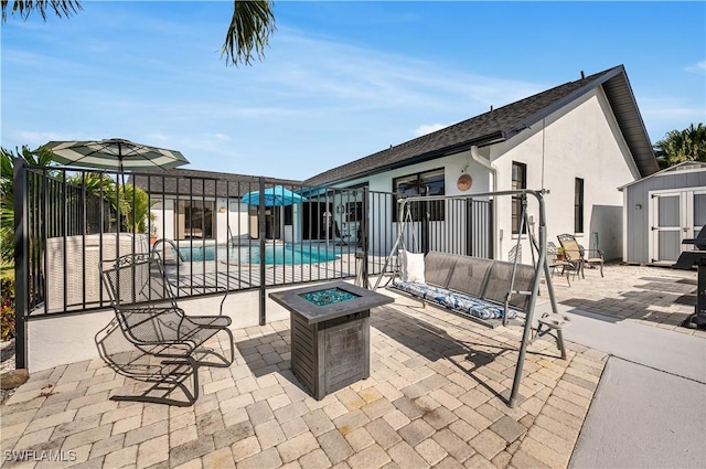 view of swimming pool featuring a shed, an outdoor fire pit, and a patio