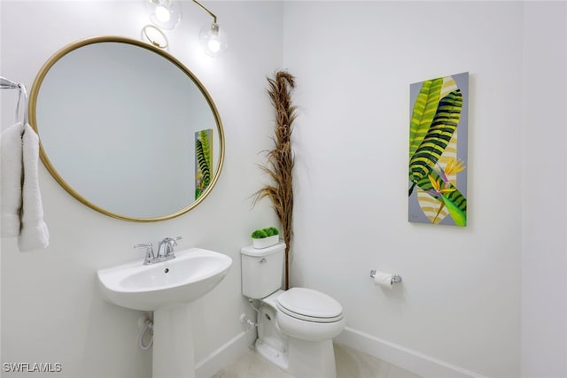 half bathroom featuring baseboards, a sink, and toilet