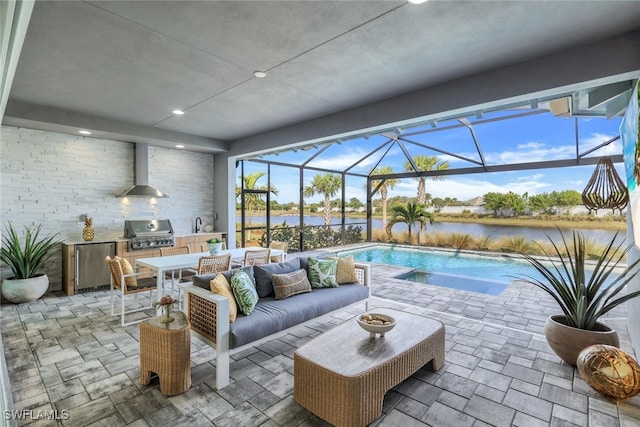 view of patio featuring a water view, grilling area, glass enclosure, exterior kitchen, and an outdoor living space