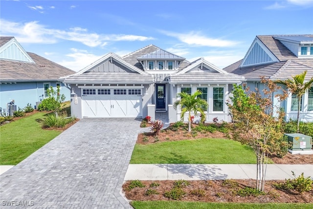 view of front of house with decorative driveway, an attached garage, board and batten siding, and a front yard