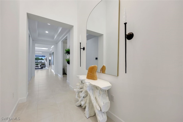 hall with a raised ceiling and baseboards