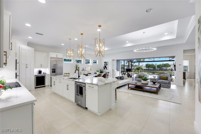 kitchen featuring stainless steel appliances, visible vents, white cabinetry, open floor plan, and a center island with sink