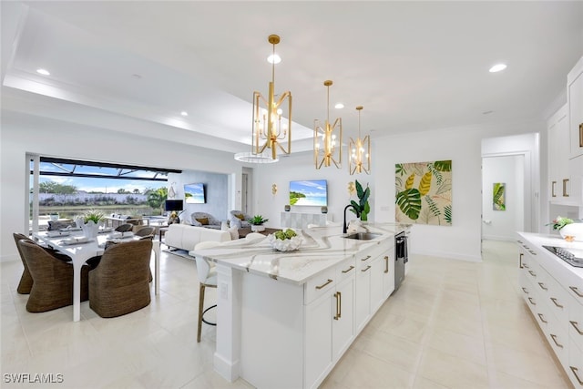 kitchen featuring a raised ceiling, light stone counters, a sink, and recessed lighting