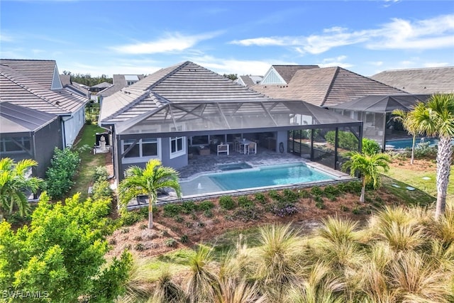 back of property with a tile roof, a lanai, a patio area, and an outdoor pool