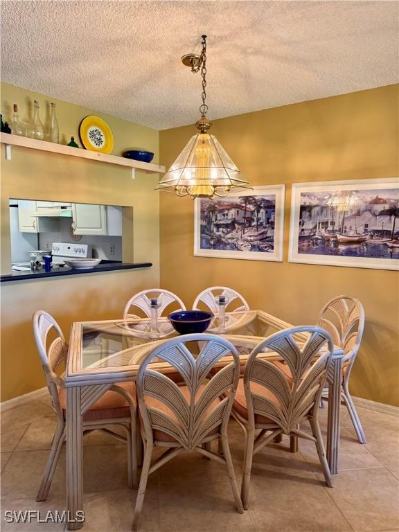 dining area featuring a textured ceiling, a notable chandelier, and light tile patterned flooring