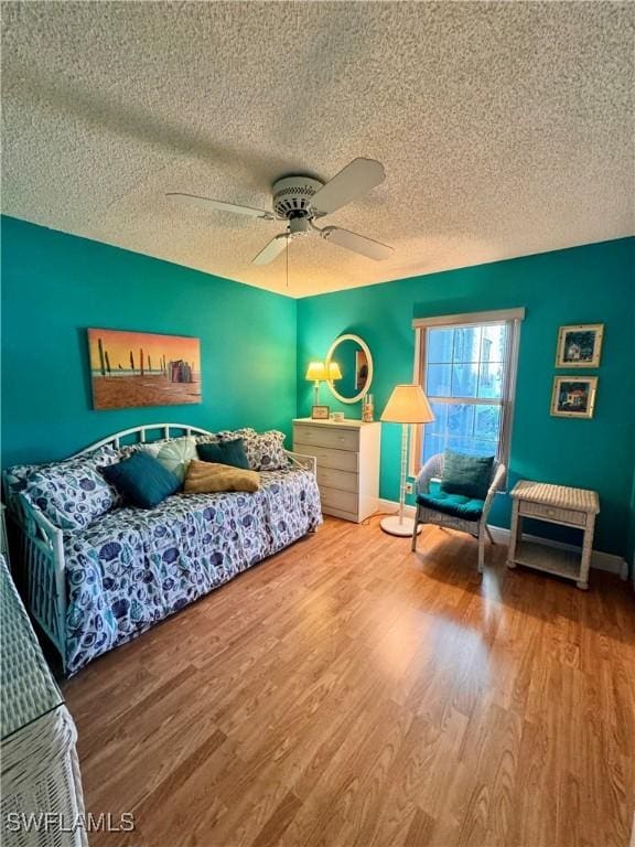 bedroom featuring ceiling fan, wood-type flooring, and a textured ceiling