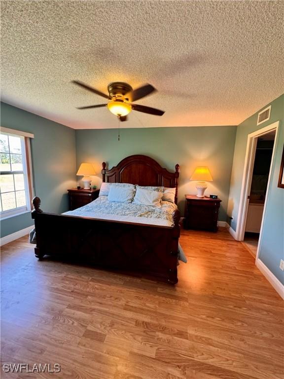 bedroom with a textured ceiling, light hardwood / wood-style floors, and ceiling fan