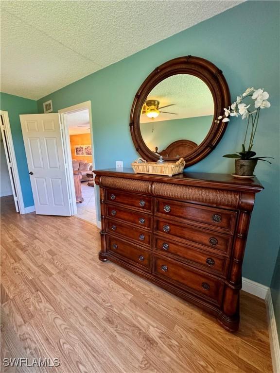 bedroom with light hardwood / wood-style floors and a textured ceiling