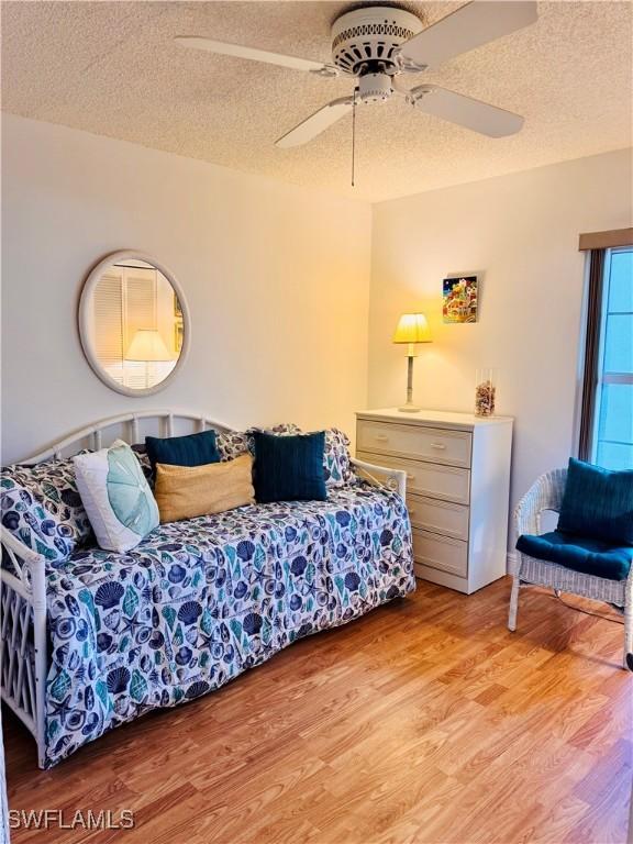 bedroom featuring ceiling fan, a textured ceiling, and light wood-type flooring