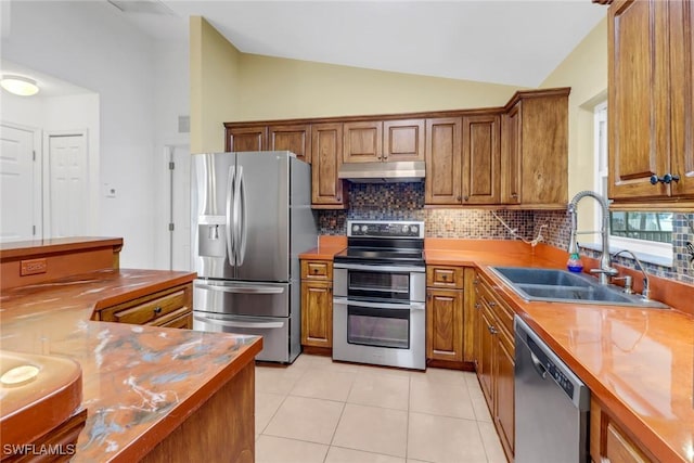 kitchen with decorative backsplash, stainless steel appliances, sink, lofted ceiling, and light tile patterned flooring